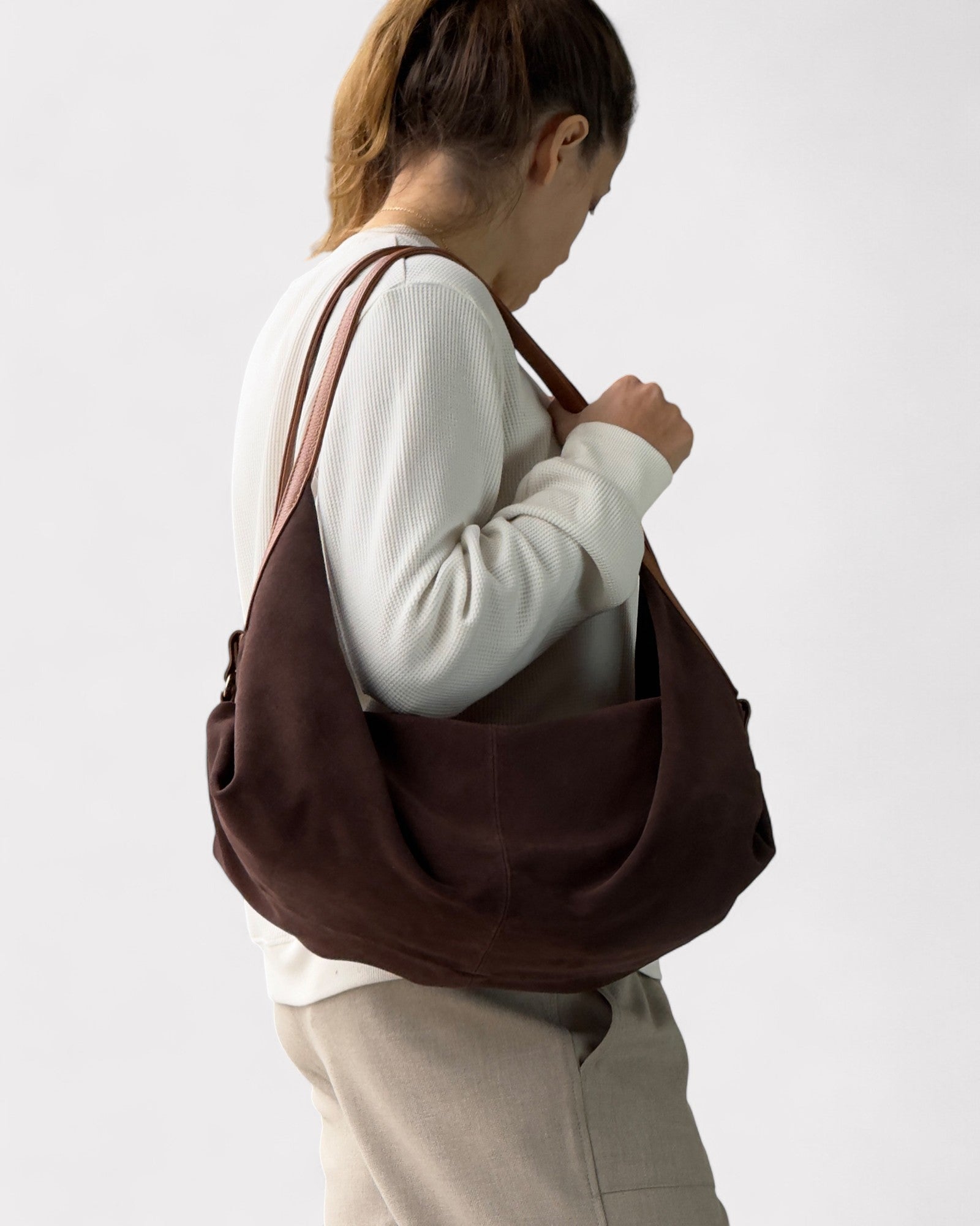 Person wearing a brown shoulder bag on a plain background
