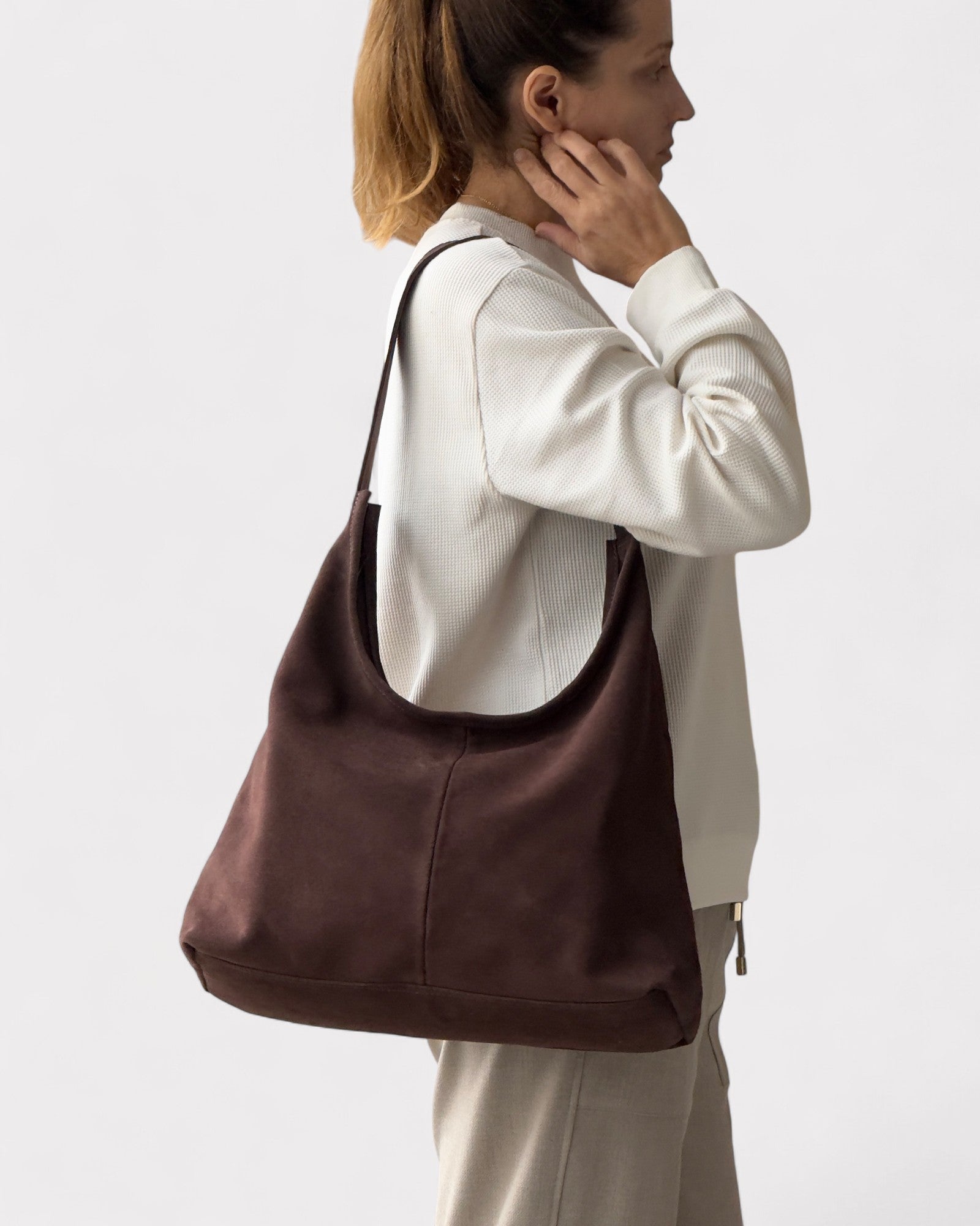 Woman carrying a brown leather bag on a plain background