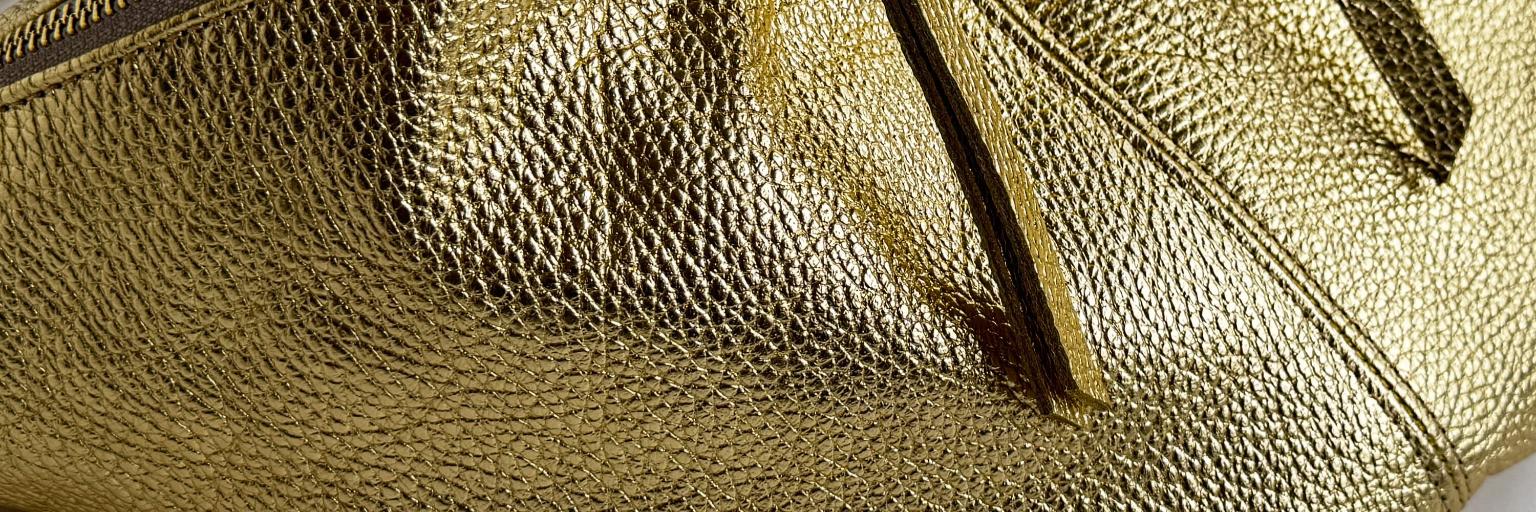 Close-up of a gold textured metallic leather bag with a zipper