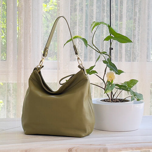 Green handbag on a surface with a plant in the background